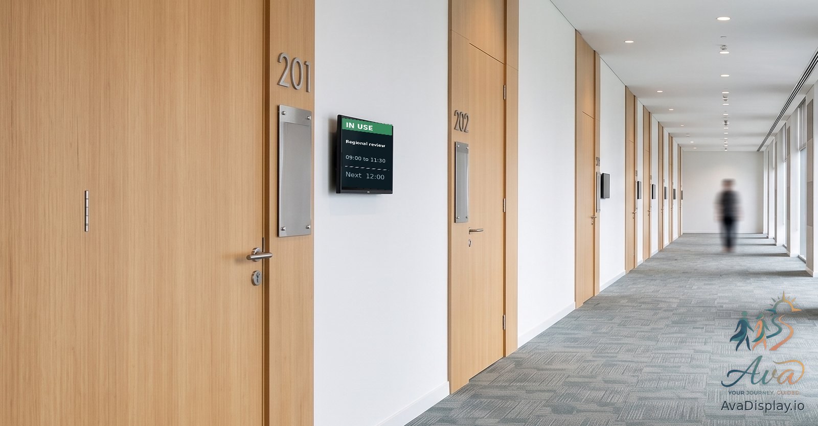 A small screen beside a meeting room door showing the meeting in progress